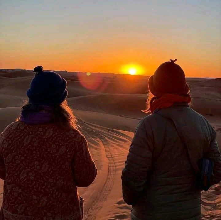 Two guests watching the sunrise over Sahara dunes