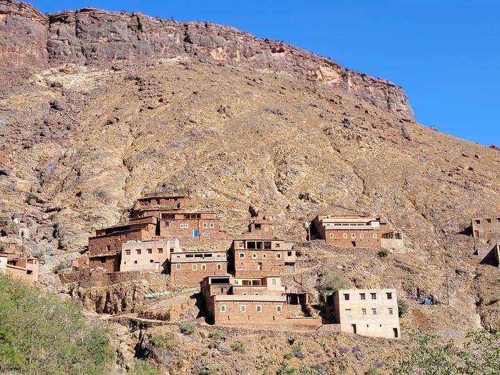 Mud-brick houses clustered on a steep hillside under a rock wall