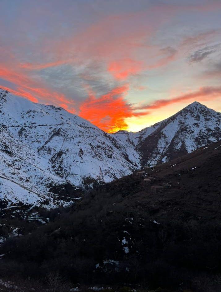 Snow-covered peaks under a fiery red sunrise sky